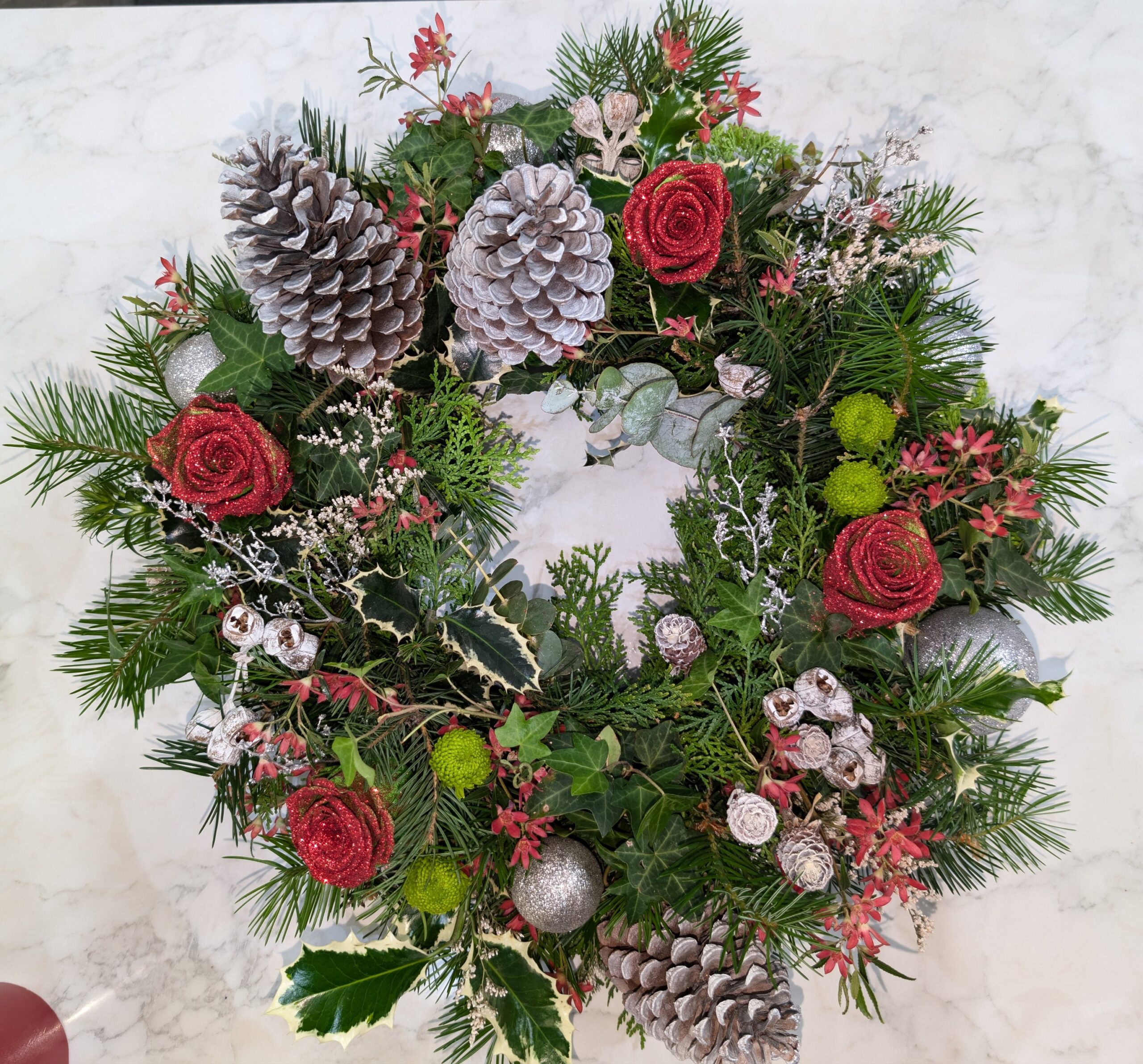 a wreath with pine cones and flowers